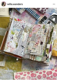 an open book sitting on top of a table covered in lots of different colored papers