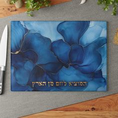 a blue flower with hebrew writing on it next to a knife and some other items