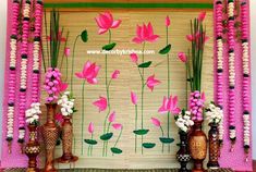 some vases and flowers are sitting on the floor in front of a decorated wall