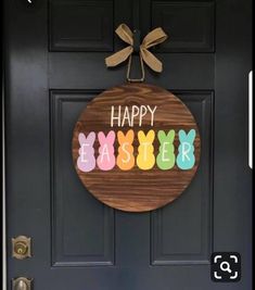 a wooden sign that says happy easter hanging on the front door with bunny ears painted on it