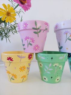 four flower pots painted with different colors and designs on them, sitting next to each other