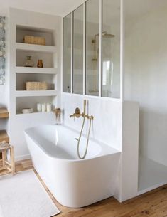 a white bath tub sitting inside of a bathroom next to a wooden floor and wall