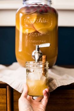 a person holding a glass jar with liquid in it