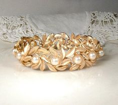 Offering a gorgeous brushed gold vintage pearl leaf shaped link bracelet.  This will be the perfect "Something Old" shower gift for the Bride. It features ornate brushed gold leaf shaped links that are adorned with lustrous glass ivory pearls.  I just love the contrast of the brushed gold against the pearls.  It just glows as it catches the light.  (This listing is for the bracelet only.)  It measures about 7 1/4 inches (18.1 cm) long when clasped and is about 5/8 inch (1.6 cm) wide.  Bracelet is in near PRISTINE condition with no signs of wear to the pearls or the gold finish front or back.  Closes with a fold over clasp. This has a nice weight and just feels good on. This stunning bracelet would be perfect for your big day or your jewelry collection.  ** At this writing, I offer the matc Ivory Pearl Necklace, Gold Leaf Necklace, Vintage Rhinestone Jewelry, Pearl Bangle, Bangles Jewelry Designs, Vintage Pearl, Wedding Jewelry Bracelets, Leaf Jewelry, Rhinestone Bridal