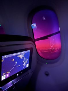 the view from inside an airplane looking out at the sky and clouds with purple lights