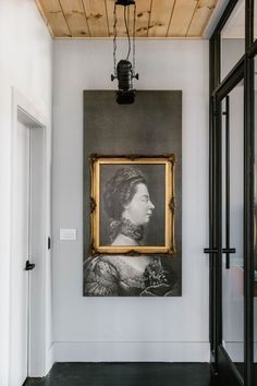 a painting hanging on the wall next to an open door with a light fixture above it