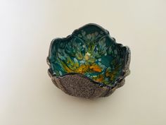 a green and yellow bowl sitting on top of a white table next to a wall