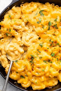 a skillet filled with macaroni and cheese on top of a white table