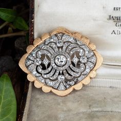 This gorgeous vintage filigree diamond brooch features a pierced design and is bordered with milgrain edging. The brooch is centered with one (1), bezel set, round brilliant cut diamond and surrounded by a total of one hundred forty-four (144), bezel/bead set, round transitional/single cut diamonds. The brooch measures 41.0mm X 33.8mm and finished with platinum pin stem and catch. The 14k yellow gold jacket was added to the brooch sometime later, we can remove it to revert it back to original. Classic White Gold Brooch With Brilliant Cut, Vintage White Gold Brooches With Brilliant Cut, Classic White Gold Brooches With 17 Jewels, Elegant Round Brooch With Intricate Design, Diamond Brooches In Brilliant Cut White Gold, White Gold Diamond Brooch With Brilliant Cut, Elegant Round Brooches With Intricate Design, Elegant Yellow Gold Wedding Brooches, Classic Diamond Brilliant Cut Brooch