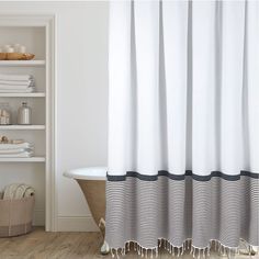 a bath tub sitting next to a white shelf filled with towels and other bathroom items