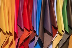 many colors of fabric hanging on a wall