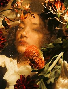 a woman is surrounded by flowers and leaves