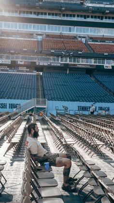 a man sitting in the middle of a stadium with his feet up on some chairs