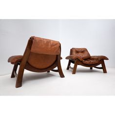 two brown leather chairs and one chair with footstools