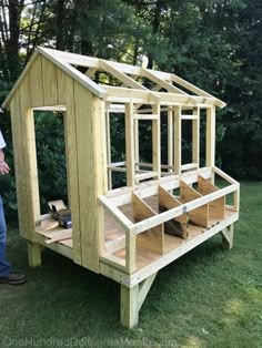 a man standing next to a small wooden structure