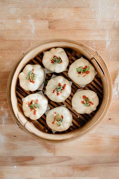 a bamboo basket filled with dumplings on top of a wooden table