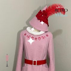 a woman's pink coat with red feathers on the collar and back, in front of a white wall