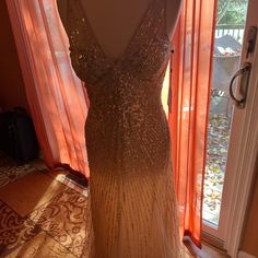 a dress that is sitting on a mannequin in front of a window with orange curtains