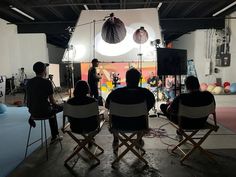 a group of people sitting in chairs on top of a floor next to each other