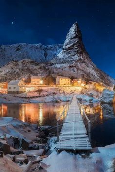 a wooden dock in front of a snowy mountain