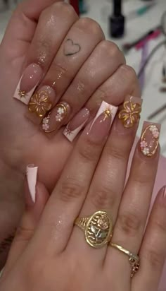 a woman's hands with gold and pink nail polish