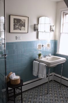 a bathroom with blue tiles and a white sink in the corner next to a window