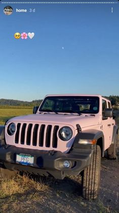 a pink jeep parked in the middle of a field with two balloons flying above it