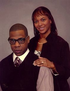 a man and woman posing for the camera with one pointing at the camera while wearing glasses