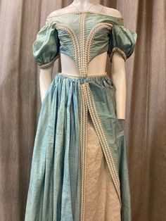 This is an amazing theatrical skirt and bodice made in the 18th century style - think Marie Antoinette and Dangerous Liaisons, although it could also be styled for a more 19th Century look - think  Bridgerton. It comes in a pale Rococo blue with cream trimmings and a cream underskirt. The main fabric in powder blue is a silk taffeta and the cream underskirt has a floral jacquard fabric, although I'm unsure what type of fabric it is made from.  The bodice has boning at the front and is designed t Blue Baroque Victorian Dress For Costume Party, Fitted Blue Victorian Baroque Dress, Regency Overbust Bodice For Costumes, Regency Style Overbust Bodice For Costume, Fitted Blue Victorian Dress For Fancy Dress Events, Blue Regency Style Victorian Costume Dress, Victorian Fitted Costume For Fancy Dress, Vintage Medieval Dress With Fitted Bodice For Costume Party, Fitted Vintage Medieval Dress For Theater