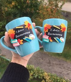 someone holding two coffee mugs with writing on them