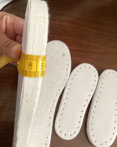 someone is measuring the height of their white shoes with a yellow tape on top of them