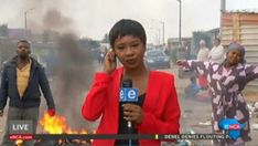 a woman talking on a cell phone while standing in front of a fire with other people