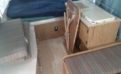 the interior of a small camper with a bed, desk and chair next to it