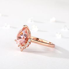 This captivating engagement ring features an enchanting pear-shaped morganite that radiates blushing hues at the center. Sparkling round stones dance down the band, which is fashioned in romantic rose gold tone sterling silver.Carat Weight: 1.815 ctStone Size: 7*10 mmNumber of Stones: 1 Stone Shape: PearStone Color: Fancy PinkCarat Weight: 0.7 ctStone Size: 2*3,1.5 mmStone Type: Jeulia® StoneNumber of Stones: 9 Stone Shape: Pear, RoundStone Color: Diamond WhiteWeight: 3.1 gWidth: 2.66 mmHeight: 5.9 mmThickness: 1.2 mmMaterial: 925 SilverPlating Color: Rose Gold Pink Pear-shaped Formal Rings, Pink Pear-shaped Ring With Rose Cut Diamonds, Formal Pink Pear-shaped Diamond Ring, Pear-shaped Morganite Jewelry, Morganite Pear-shaped Fine Jewelry Ring, Pear Cut, Romantic Roses, Morganite, Pear Shaped