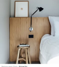 a small stool next to a bed with a lamp on top of it in a bedroom