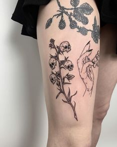 a woman's leg with tattoos on it and flowers growing out of the thigh