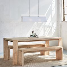 a wooden table with two benches and a vase on it in front of a window