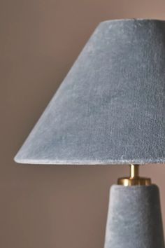 a gray lamp with a gold base and a light blue shade on the bottom is shown