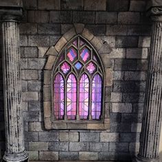 an old stone building with columns and a stained glass window in the middle of it