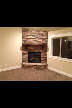 an empty living room with a stone fireplace