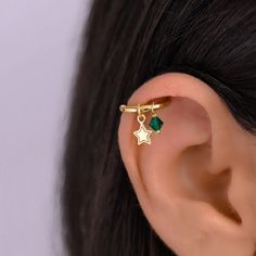 a close up of a person's ear wearing an ear cuff with a star design on it