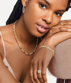 a woman with braids wearing a white top and gold jewelry on her left arm