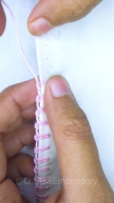 two hands are working on an object with yarn and thread in the shape of a spiral