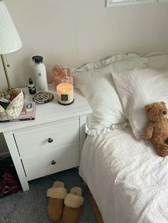 a teddy bear sitting on top of a bed next to a night stand and lamp