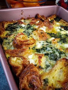 a casserole dish with spinach, cheese and other toppings in a pan