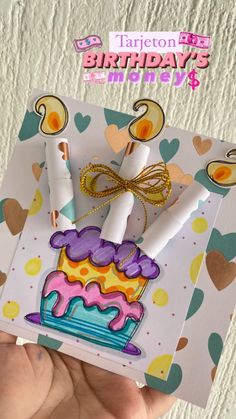 someone holding up a birthday card with two candles on it and a cake in the middle