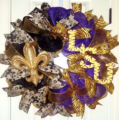 a purple, gold and black wreath with a fleur de lis on it