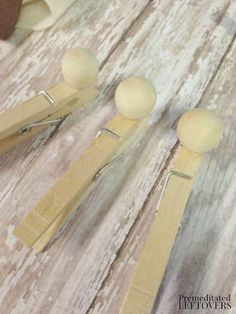 three wooden spoons are sitting next to each other on a wood table with some paper clips sticking out of them