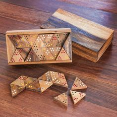 a wooden box filled with dices sitting on top of a wooden floor next to a piece of wood