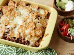 a casserole dish with meat, cheese and vegetables next to it on a table